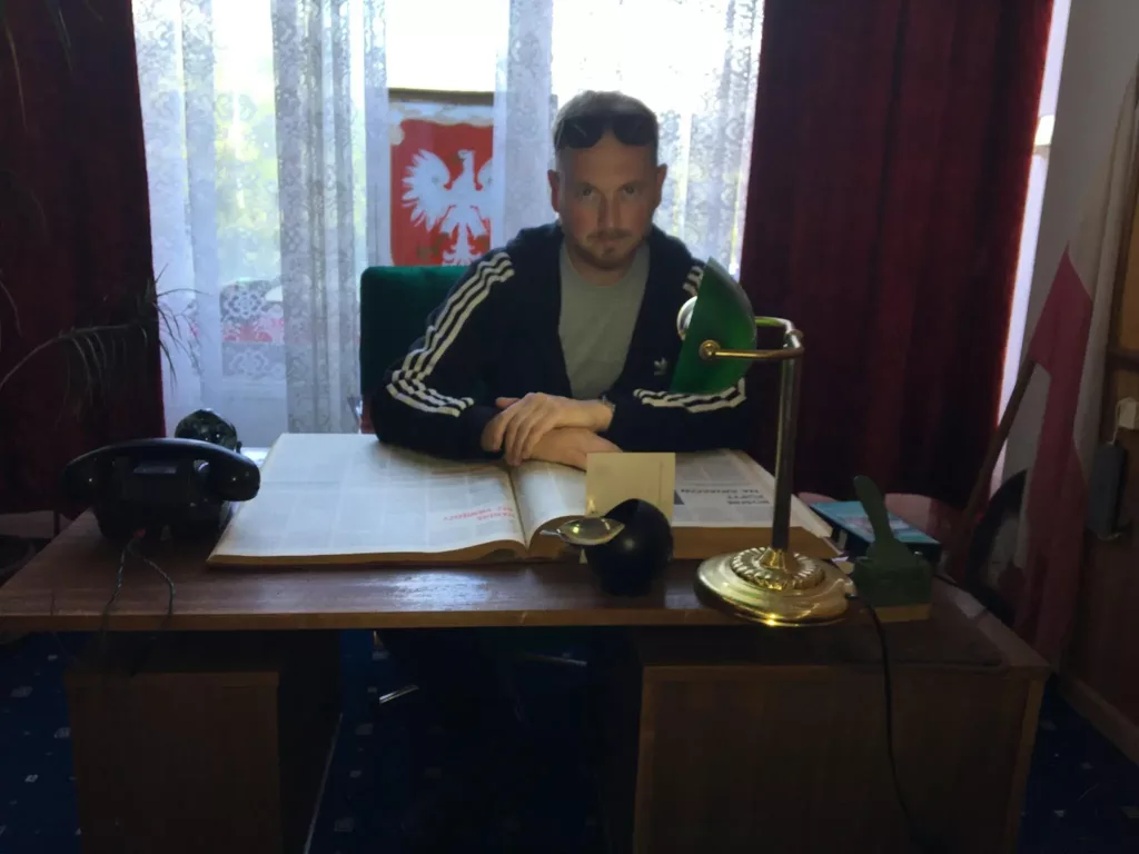 Łukasz sitting on a desk working on his projects.