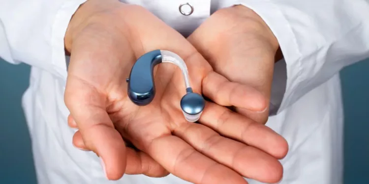 A person holding a hearing aid in his hands.