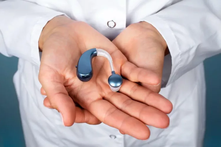 A person holding a hearing aid in his hands.