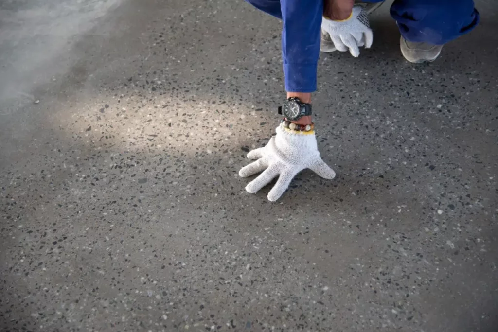 a man touching driveway by wearing gloves.