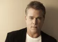 Ray Liotta posing in white tee and black coat