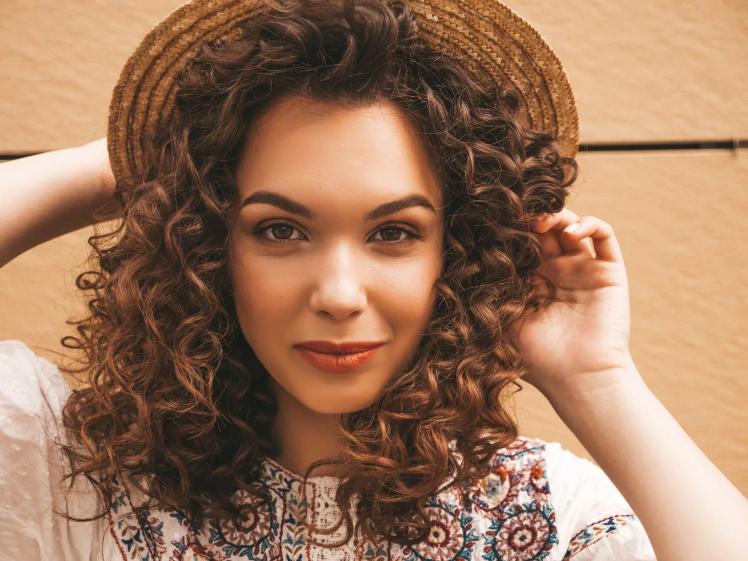 girl with curly hair wearing a hat