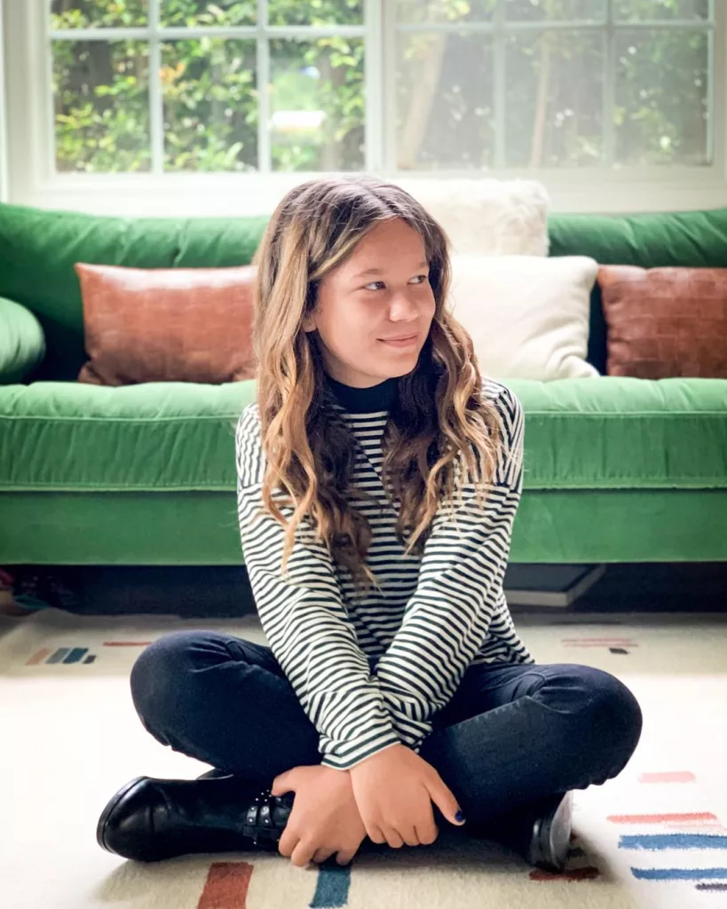 Weslie sitting on the floor wearing striped top and black bottom.