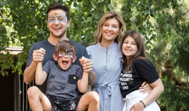 Kiril Zelenskiy with his family in the picture. He is wearing grey colored clothes.