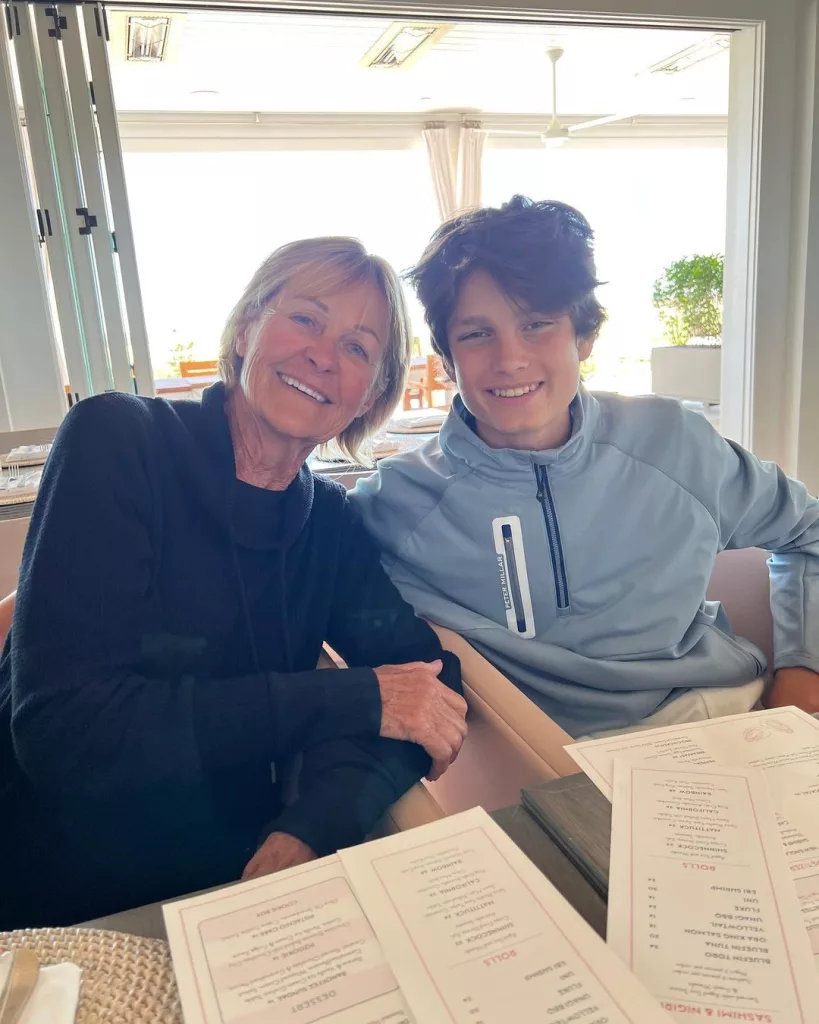 John wearing a grey jacket and posing with his grandmother.