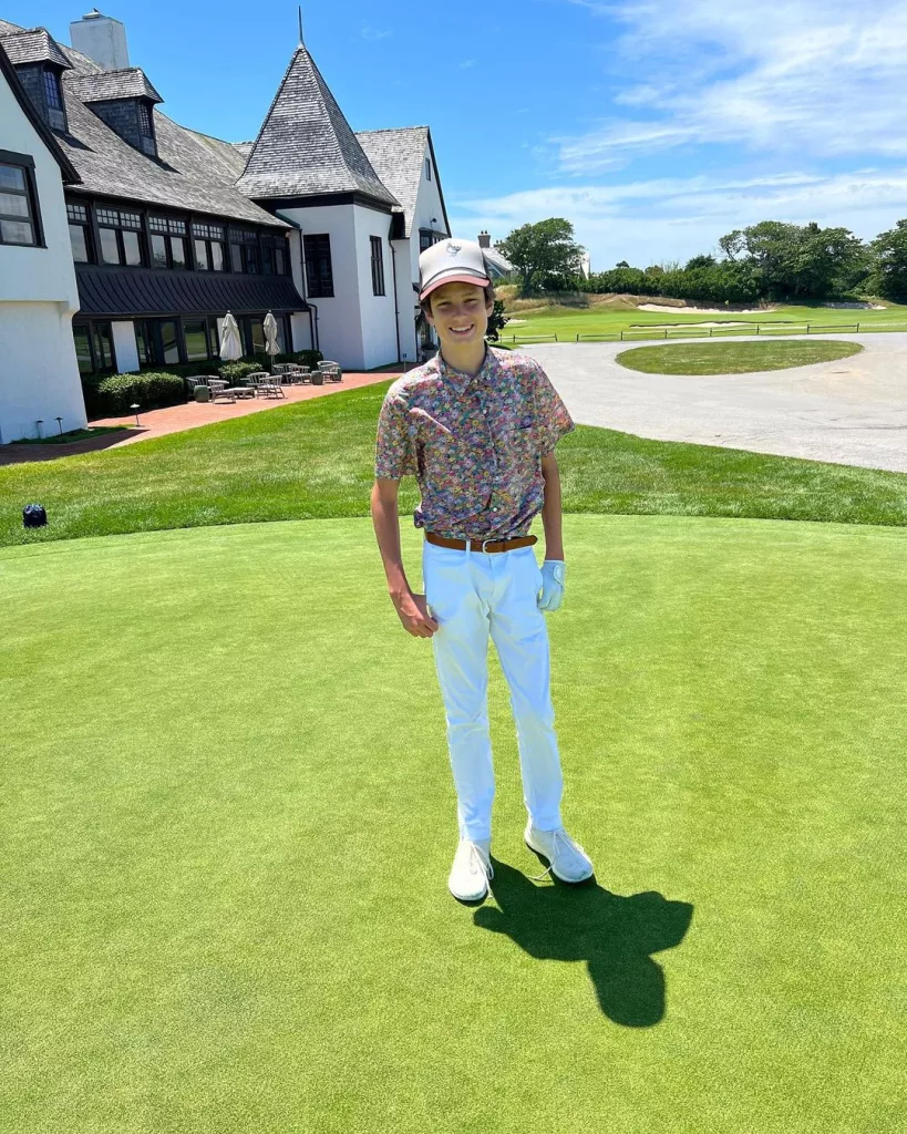 John wearing a colorful shirt with white pants and posing on a green field.