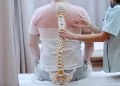 A physiotherapist measuring the spine of the patient in a therapy.