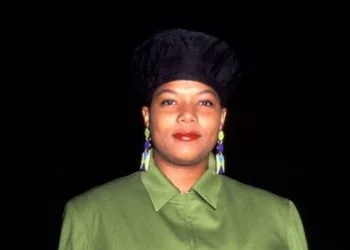Queen Latifah wearing a black cap and green collared dress.
