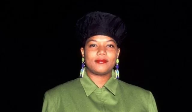 Queen Latifah wearing a black cap and green collared dress.