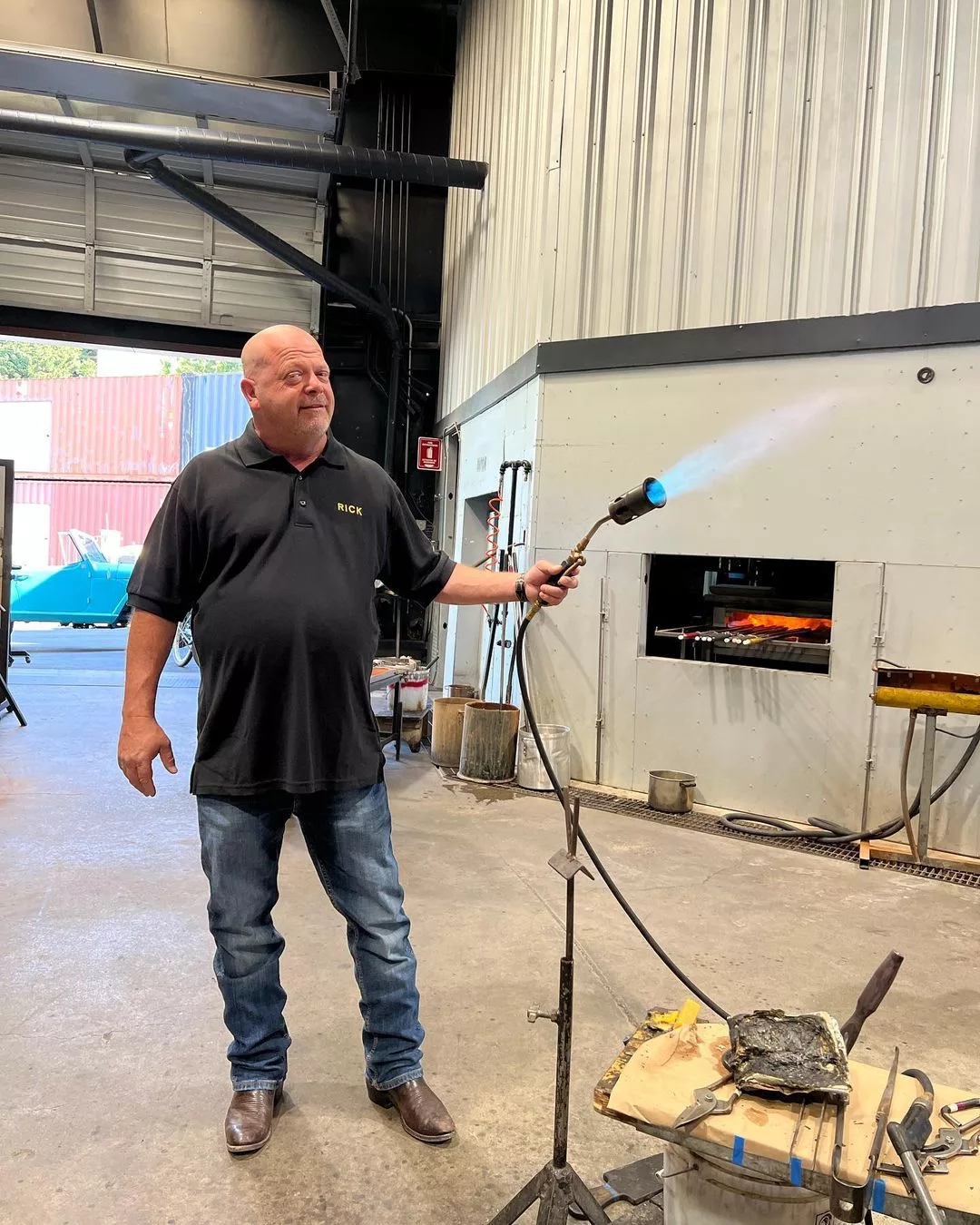 RIck Harrison holding a gas pipe in the Pawn Shop. He is wearing black polo tee and dark blue jeans. 