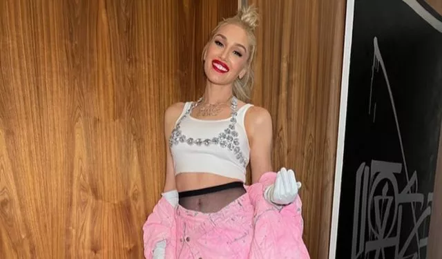 Gwen Stefani wearing a white top and light pink skirt.