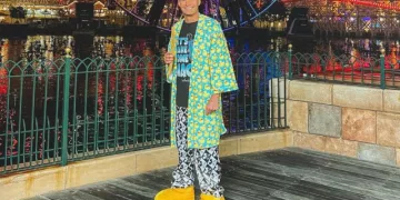 Ryan Seacrest wearing green colorful robe with black t-shirt and black printed lower. He is also wearing yellow colored shoes.