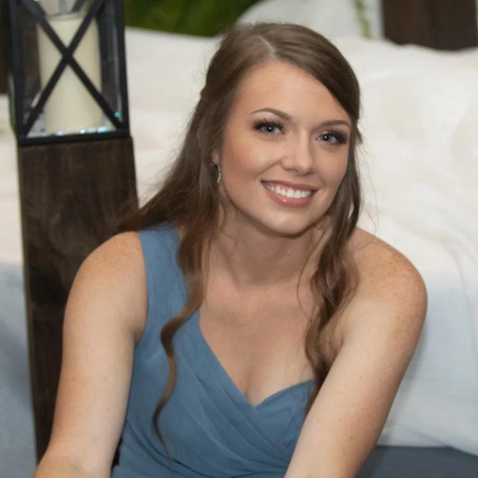 Taelyn wearing a blue colored off shoulder top and smiling.