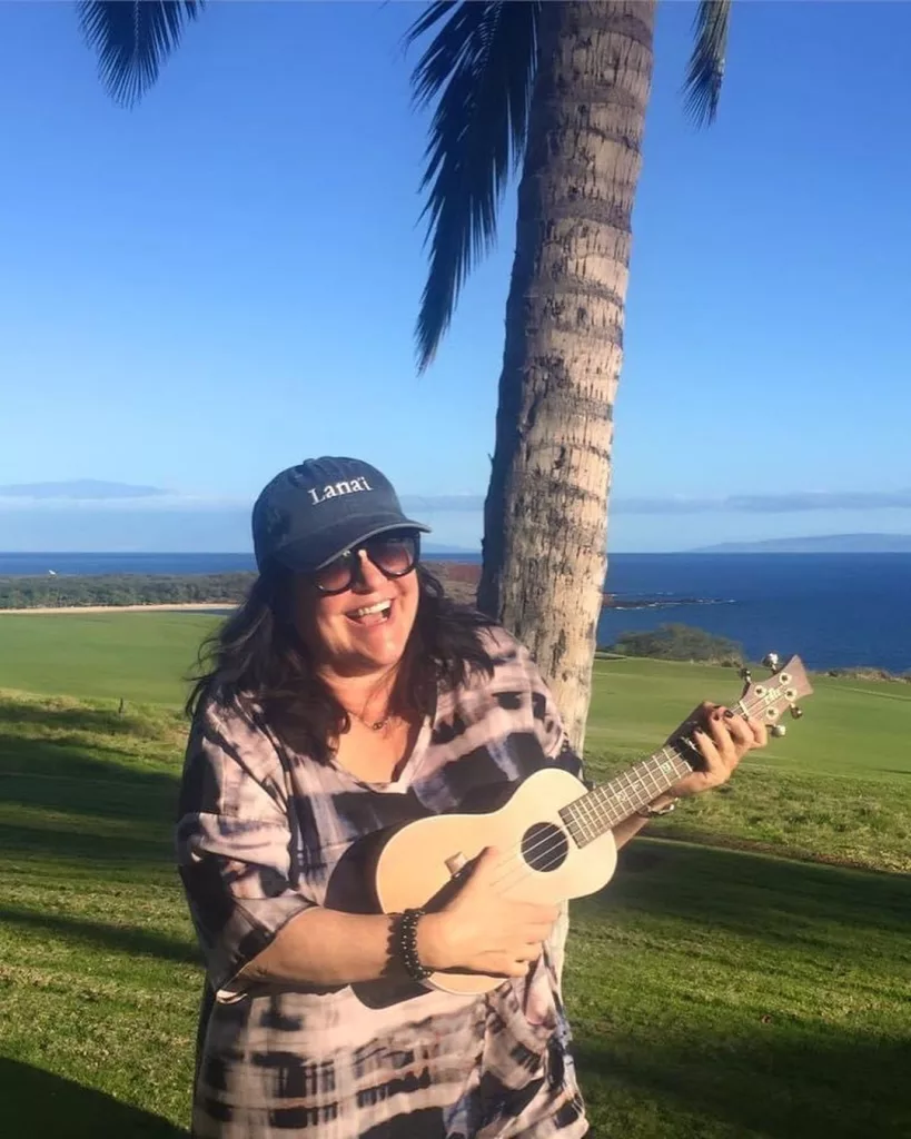 Ann playing Ukulele and wearing a cap and sunglasses.